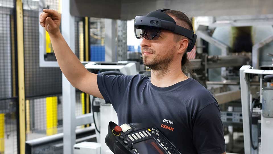 Ein Mitarbeiter von ams OSRAM trägt eine VR-Brille bei seiner Arbeit.