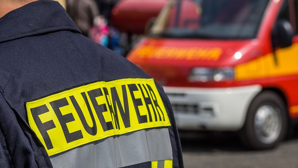 Teilansicht eines Feuerwehrmanns und eines Einsatzwagens