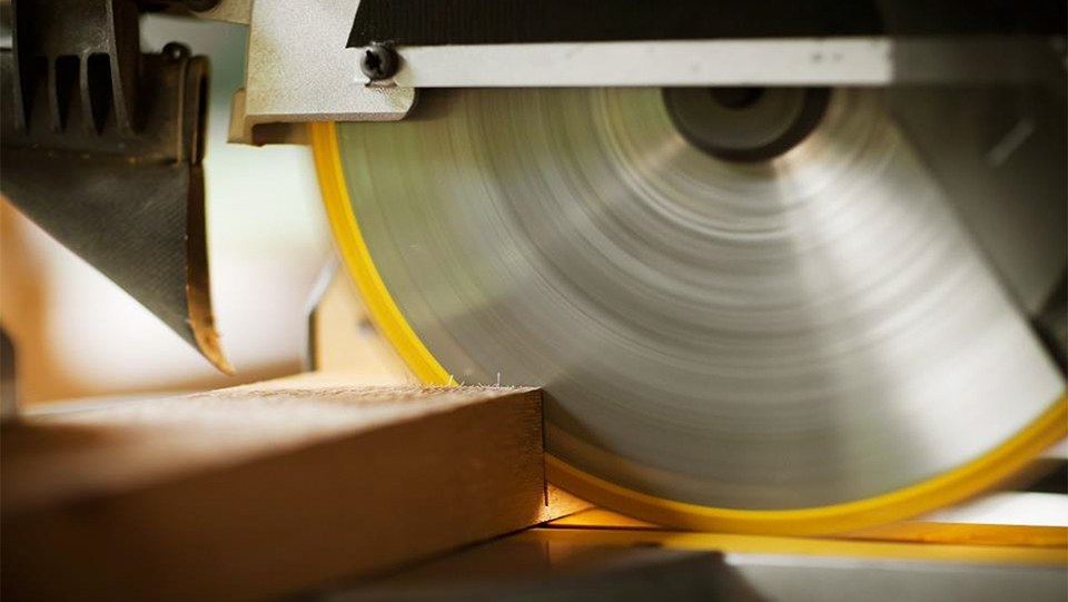 Aufnahmen des Sägeblatts einer Kreissäge beim Sägen eines Holzbalkens; das Sägeblatt scheint stillzustehen.