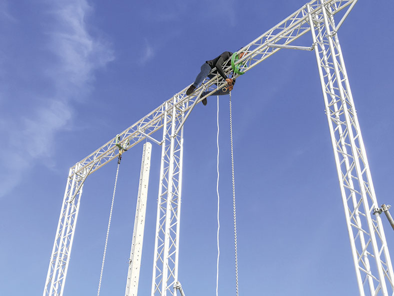 Dieses Foto zeigt einen Höhenarbeiter (Rigger) beim Aufbau einer Traverse.