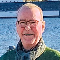 Asbest: Porträt von Thomas Strauß im Freien. Er lächelt, hat kurze helle Haare, trägt eine Brille und einen Schal über einer grünen Jacke.