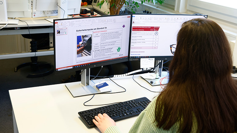 Sicherheitsimpuls BSH: Frau am Schreibtisch schaut auf PC-Bildschirm mit Intranet-Sicherheitsinfos.