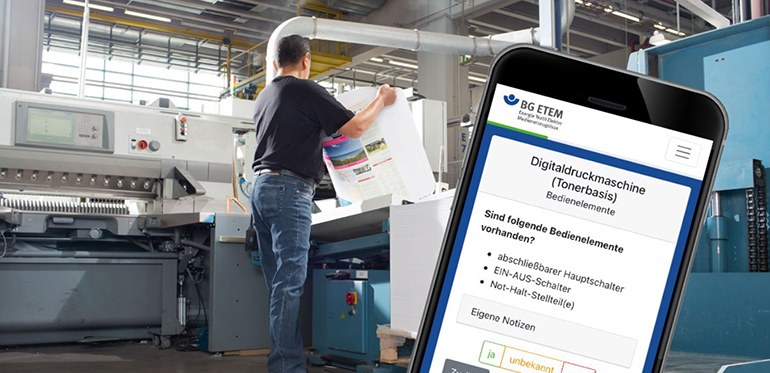 Bild eines Arbeiters in einer Druckerei mit Druckbogen in der Hand an einer Maschine, im Vordergrund ein großes Smartphone mit der BG-ETEM-Webapp auf dem Bildschirm.
