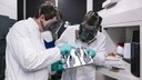 Zwei Wissenschaftler mit Werkstück an einer SLM-Maschine für Metall