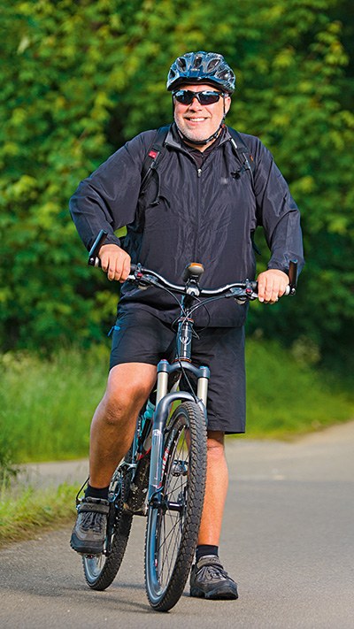 Stehender Mountainbike-Fahrer mit Fahrradhelm und Sonnenbrille