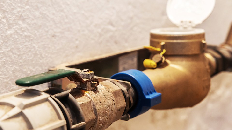 An einer Wand montierte Wasseruhr mit Zu- und Ablauf