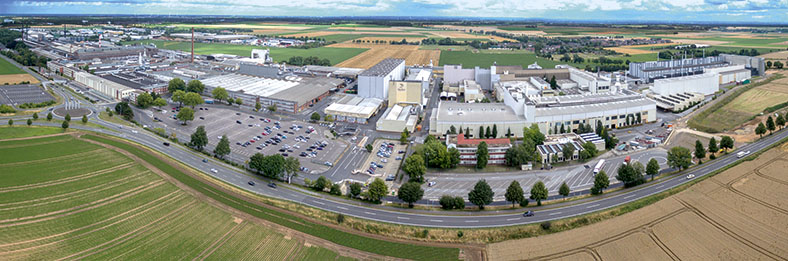Luftbild des deutschen Sitzes des norwegischen Aluminiumherstellers Hydro Aluminum Rolled Products GmbH in Grevenbroich. Man sieht verschiedene Fabrikgebäude und Parkplätze, im Vordergrund eine Straße und umliegende Felder.