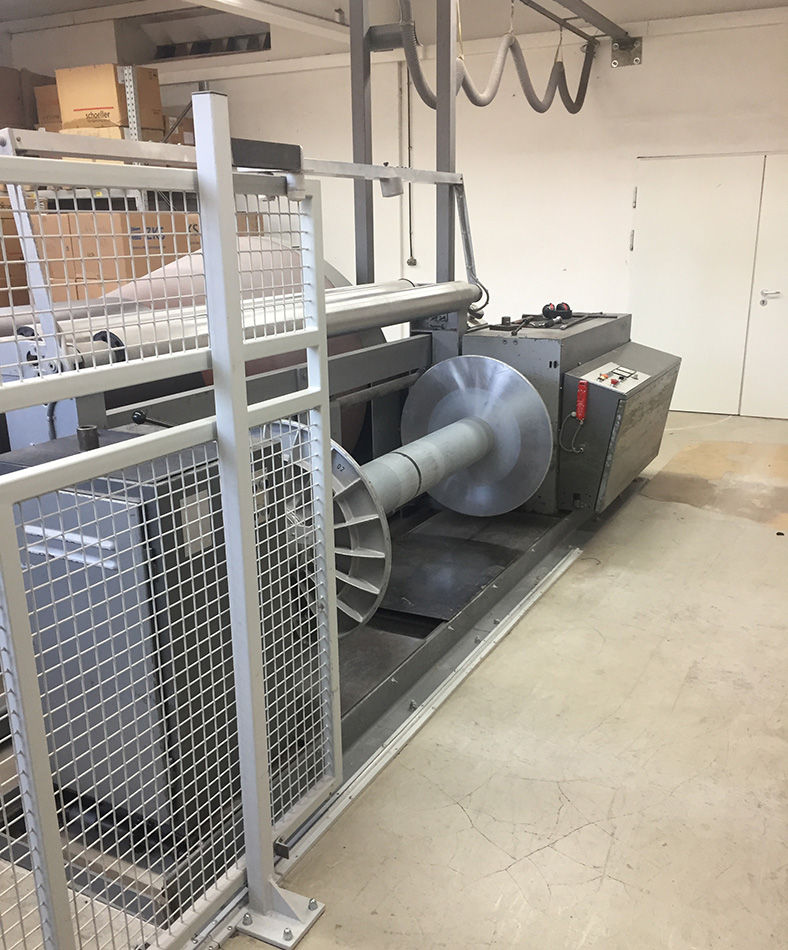 Konusschärmaschine in einer Fabrikhalle mit nachgerüstetem Schutzgitter in offener Position.