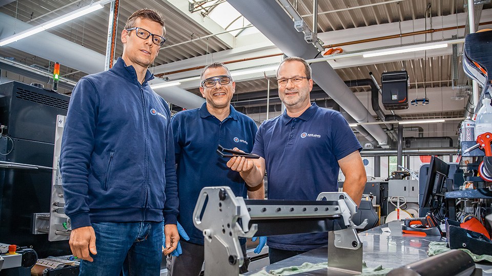 Carsten Fromm, Enis Hrbinic und Joachim Pfeil in einer Druckerei von All4Labels, vor ihnen auf dem Tisch ein Rakelmesser, einer hält die Reinigungszange in der Hand