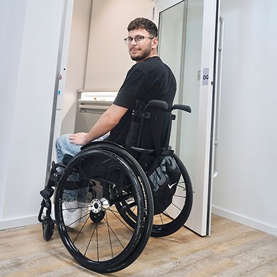 Serhat Yüksel steht mit seinem Rollstuhl in der geöffneten Tür des Fahrstuhls