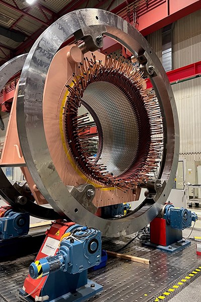 Die Spule eines riesigen Elektromotors wird von zwei Rollringen so gehalten, dass ihre Öffnung von der Seite her zugänglich ist