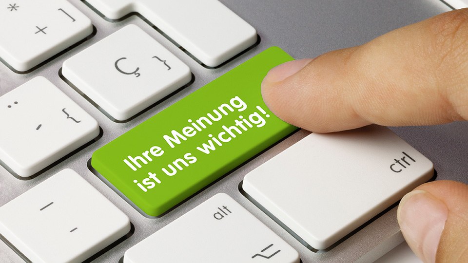 Finger drückt auf einem Laptop eine Taste mit der Aufschrift Ihre Meinung ist uns wichtig