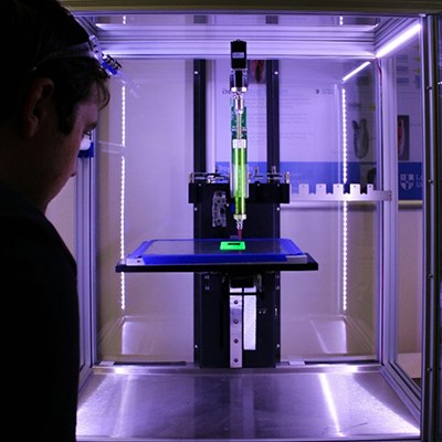 Blick in das Glasgehäuse eines 3D-Druckers, der gerade in Betrieb ist.