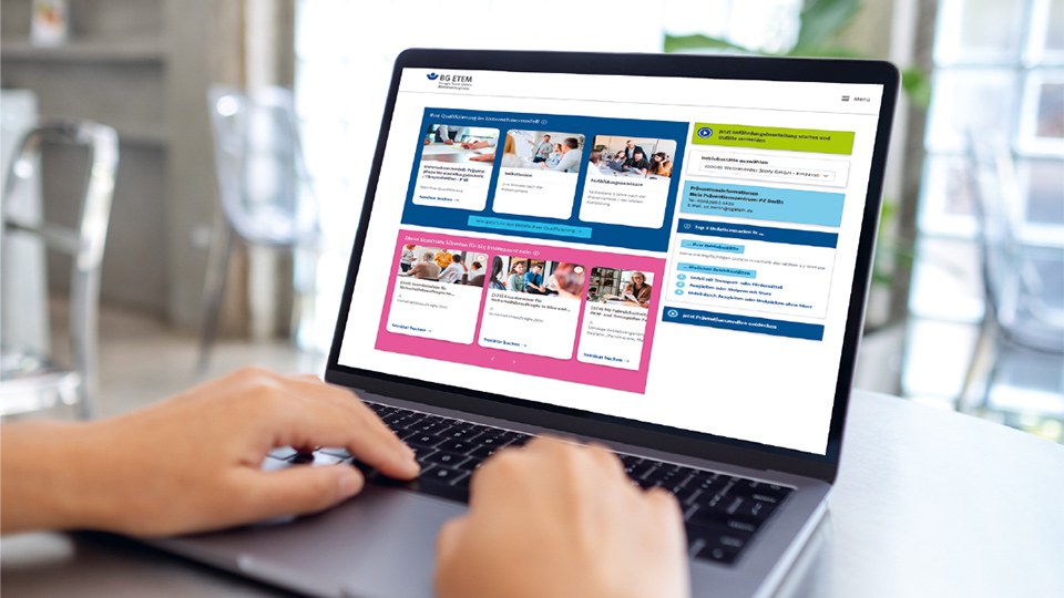 Person arbeitet an einem Laptop, auf dessen Display das Serviceportal Meine BG ETEM mit verschiedenen Kacheln zu sehen ist.