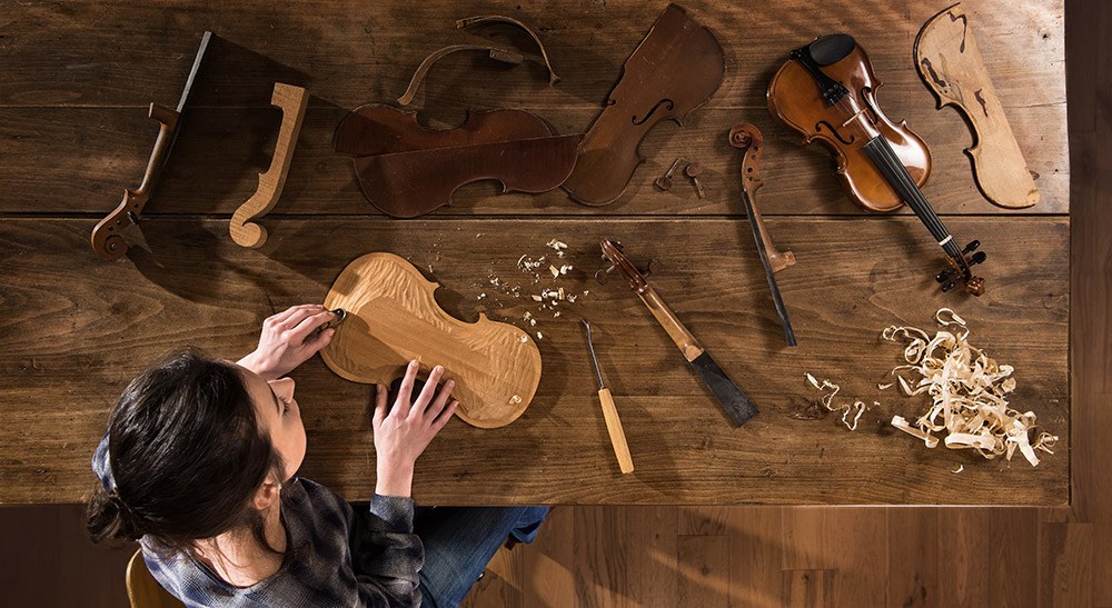 Arbeitsschutz in der Ausbildung: Instrumentenbauerin arbeitet an einer Violine.