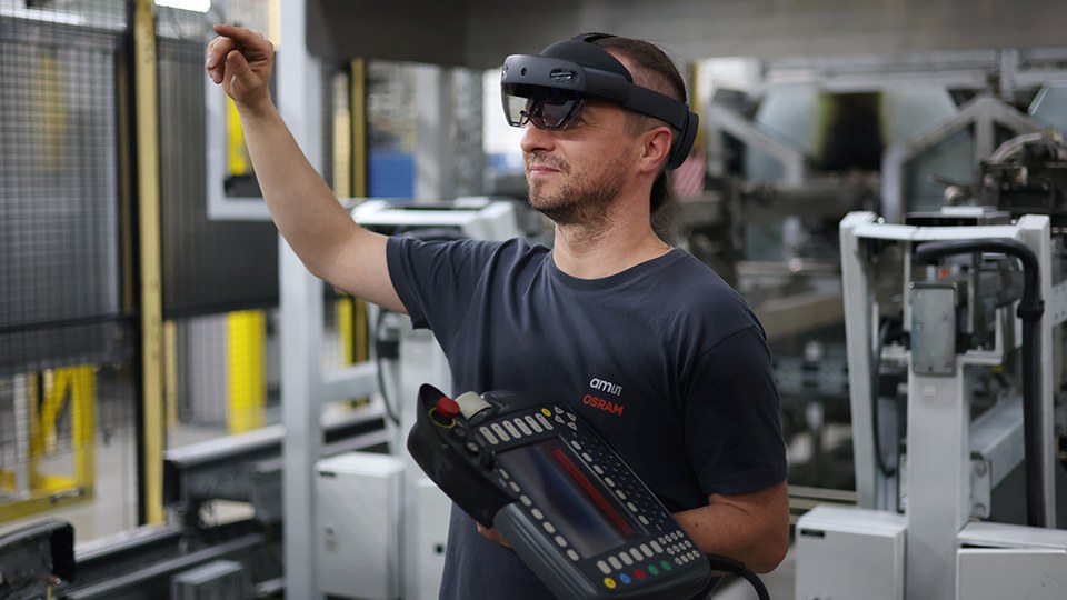 Mitarbeiter in der Produktion greift mithilfe einer Virtual-Reality-Brille durch Handbewegungen auf Maschineninformationen zu