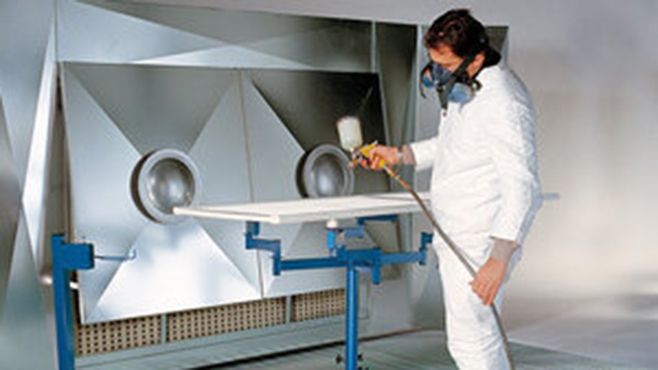Arbeiter mit Overall und Schutzmaske beim Lackieren in einem Lackierraum