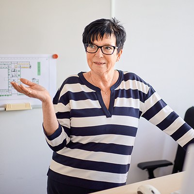 Teamleiterin Ina Drysch steht an einem Schreibtisch, sie ist im Gespräch und gestikuliert
