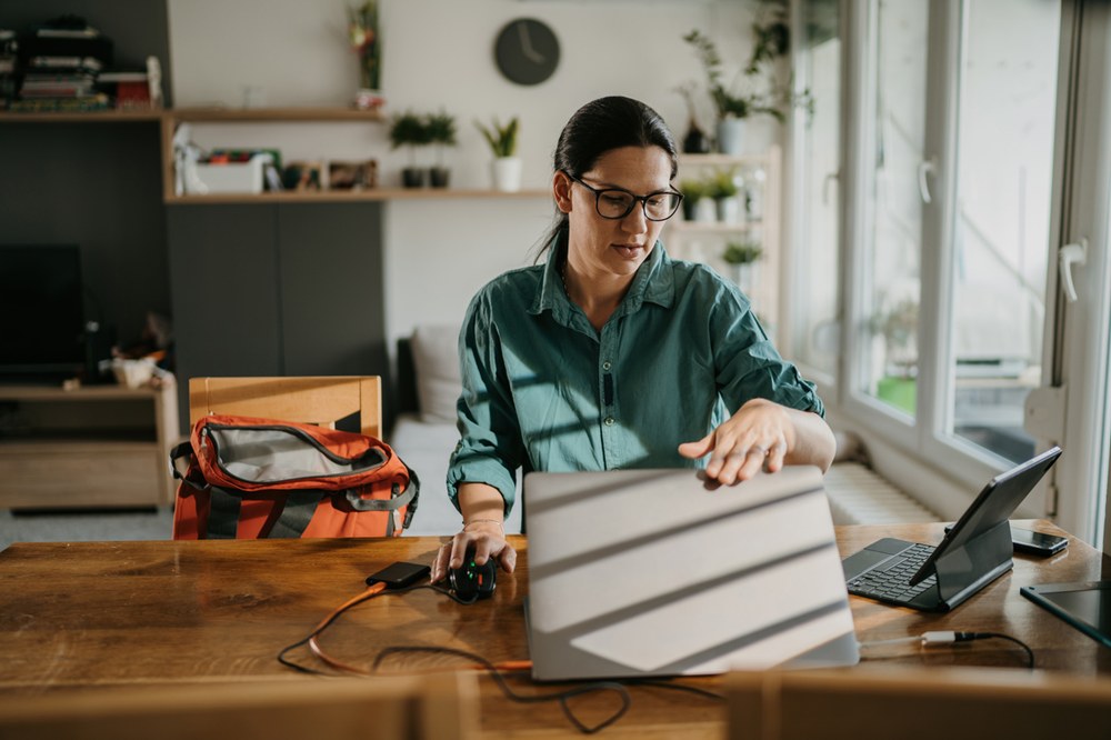 Frau klappt an ihrem Schreibtisch im Homeoffice ihren Laptop auf