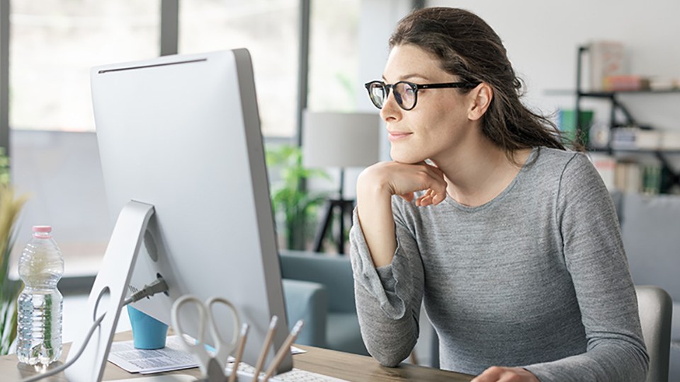 Frau sitzt im Homeoffice vor ihrem Computer und arbeitet