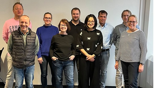 Gruppenbild des Prüf- und Beratungsteam, das sich in zwei Reihen aufgestellt hat und frontal fotografiert ist:  Uwe Leu, Charlene Elsner, Dennis Wolf, Gerd Stuber, Andre Teichner und in der oberen Reihe Branko Spiegler, Andrea Lutz, Maria Ferraro und Christine Garm. Alle schauen in die Kamera.