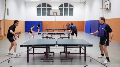 Turnhalle, in der an drei Platten Tischtennis gespielt wird