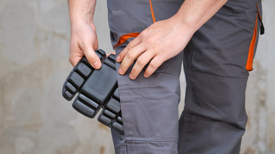 Handwerker schiebt ein Kniepolster in seine Arbeitshose