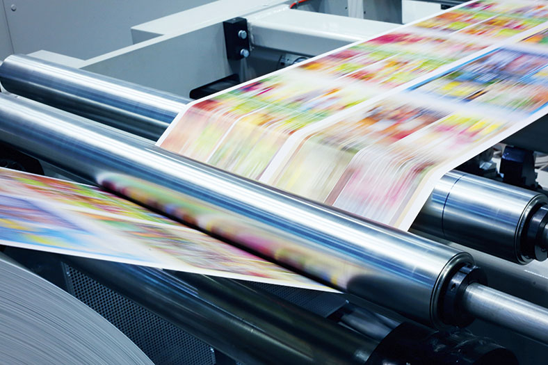 Fachtagung "Digitalisierung der Arbeitswelt": Bedrucktes Papier läuft über Walzen einer Druckmaschine.