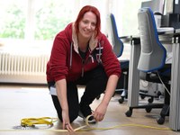 Workshop Nudging 15: Auszubildende klebt Kabel am Boden fest